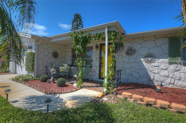 exterior space with driveway, covered porch, an attached garage, and stone siding