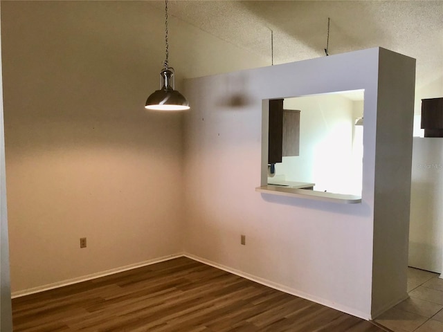 spare room with hardwood / wood-style floors, a textured ceiling, and lofted ceiling