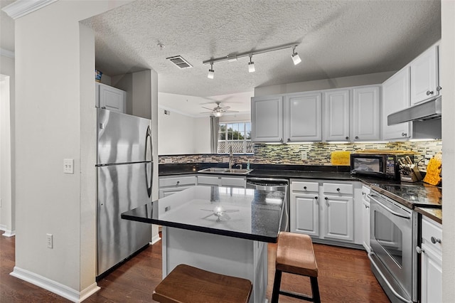 kitchen featuring dark wood-type flooring, white cabinetry, a kitchen island, stainless steel appliances, and ceiling fan