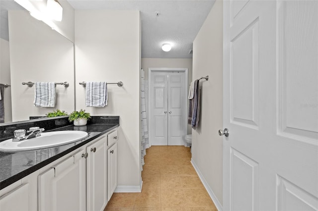 bathroom featuring tile patterned flooring, a textured ceiling, vanity, and toilet