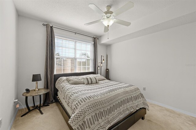 bedroom featuring ceiling fan, a textured ceiling, and light carpet