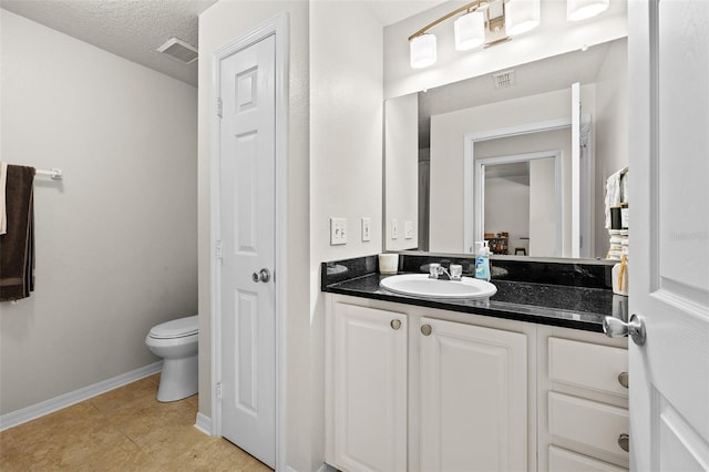 bathroom featuring tile patterned floors, a textured ceiling, vanity, and toilet