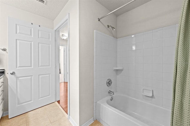 bathroom with a textured ceiling, shower / tub combo, tile patterned flooring, and vanity