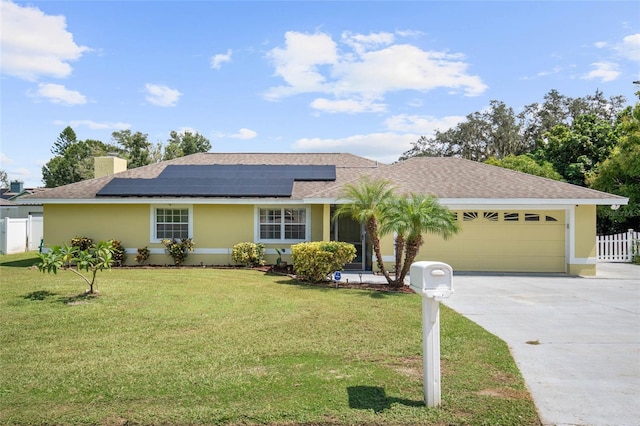 ranch-style house with a front yard, solar panels, and a garage