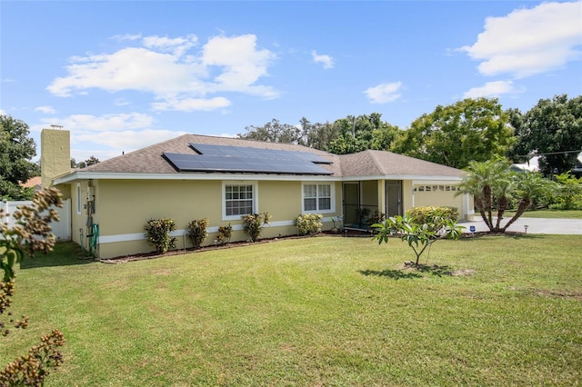 ranch-style house with a garage, solar panels, and a front lawn