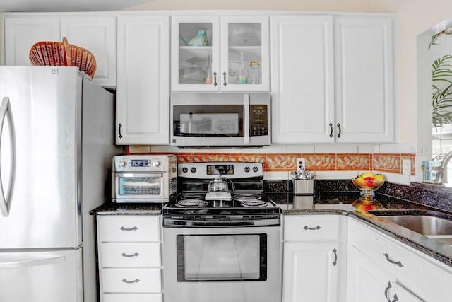 kitchen featuring dark stone counters, appliances with stainless steel finishes, sink, and white cabinets