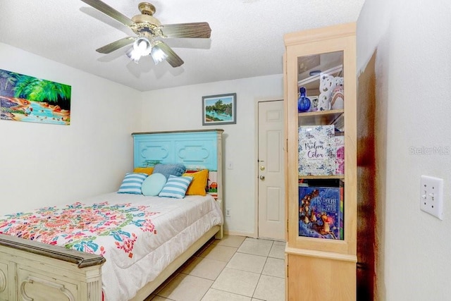 bedroom with a textured ceiling, ceiling fan, and light tile patterned floors