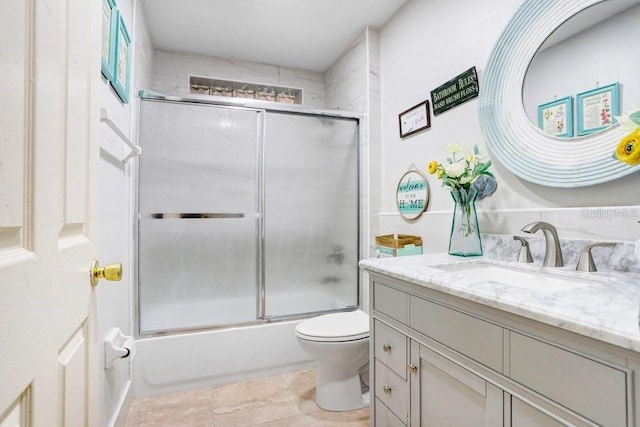 full bathroom with toilet, vanity, bath / shower combo with glass door, and tile patterned flooring