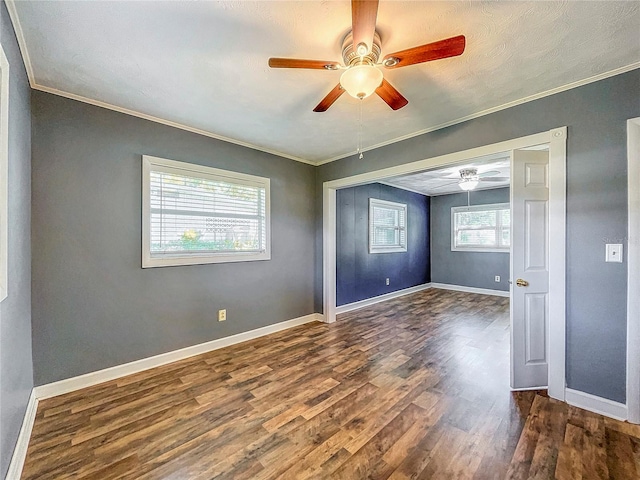 empty room with ceiling fan, dark hardwood / wood-style floors, a healthy amount of sunlight, and crown molding