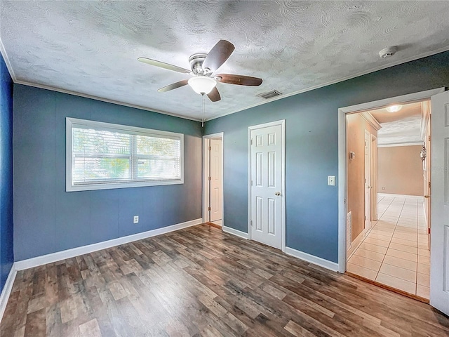 unfurnished bedroom with wood-type flooring, ceiling fan, crown molding, and a textured ceiling