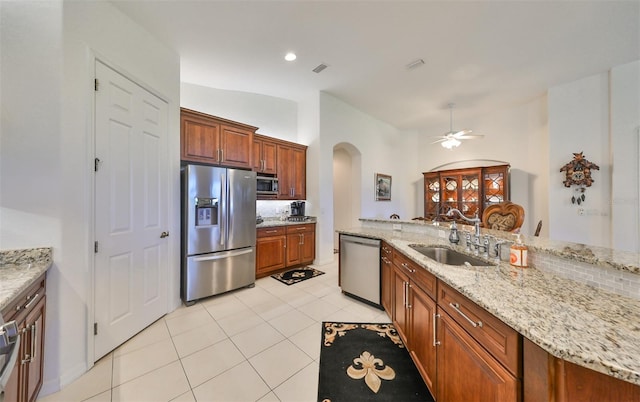 kitchen featuring light stone counters, tasteful backsplash, appliances with stainless steel finishes, ceiling fan, and sink