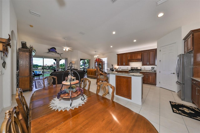 dining space with ceiling fan, vaulted ceiling, and light tile patterned flooring