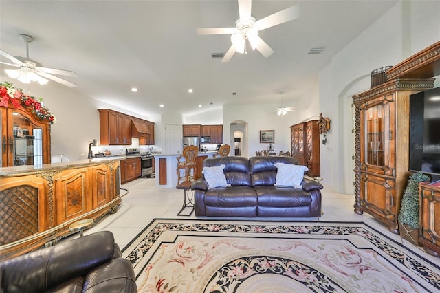 living room with ceiling fan, vaulted ceiling, and light tile patterned floors