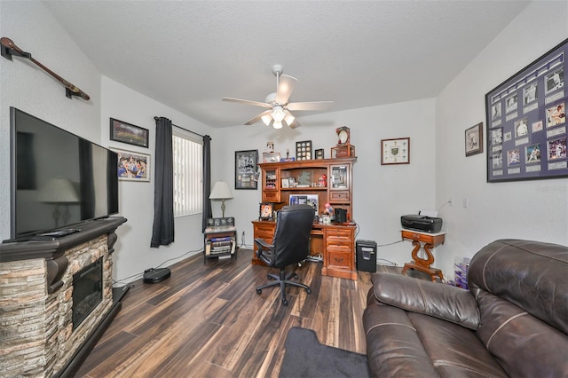 office space with a textured ceiling, ceiling fan, a fireplace, and dark hardwood / wood-style floors