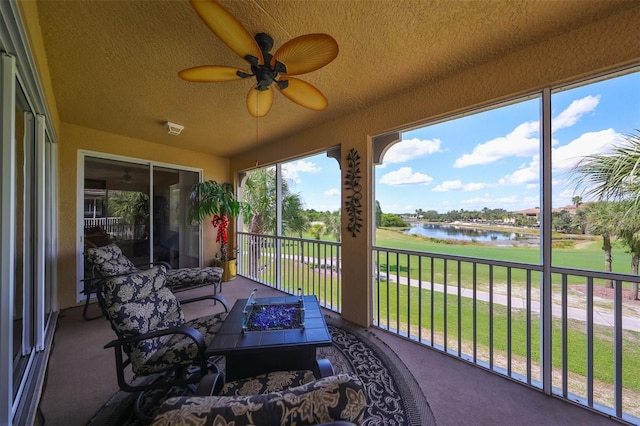 sunroom / solarium featuring ceiling fan and a water view