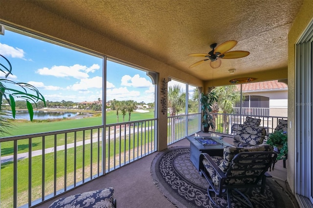 sunroom with ceiling fan and a water view