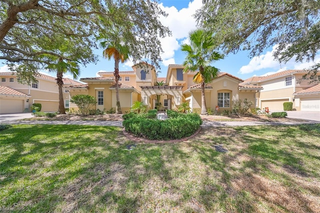 mediterranean / spanish home featuring a front lawn, a pergola, and a garage