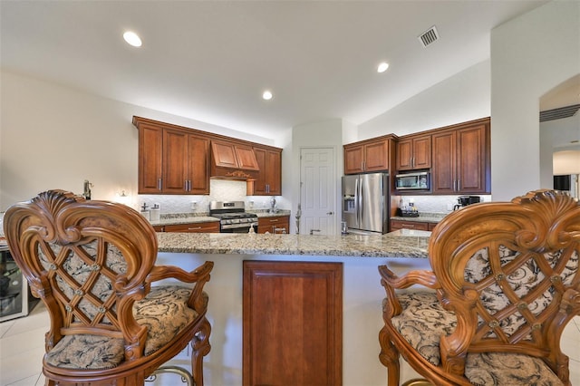 kitchen with light stone countertops, premium range hood, lofted ceiling, backsplash, and appliances with stainless steel finishes