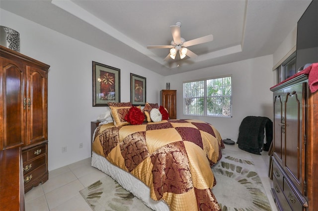 tiled bedroom featuring ceiling fan and a tray ceiling