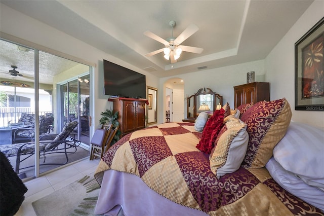 bedroom featuring light tile patterned flooring, access to exterior, ceiling fan, and a tray ceiling