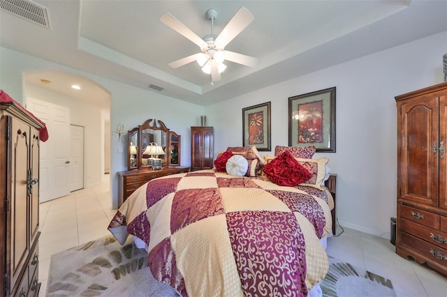 tiled bedroom featuring a raised ceiling and ceiling fan