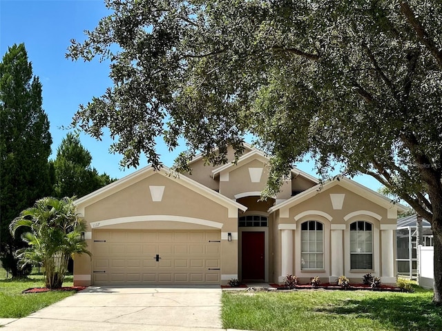 mediterranean / spanish-style home with an attached garage, a front lawn, concrete driveway, and stucco siding