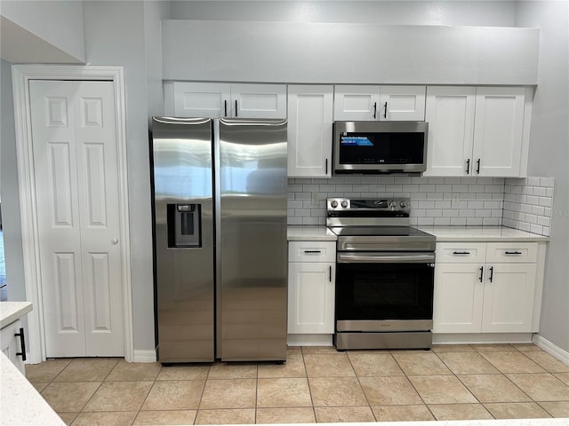 kitchen with white cabinets, light tile patterned floors, stainless steel appliances, and backsplash