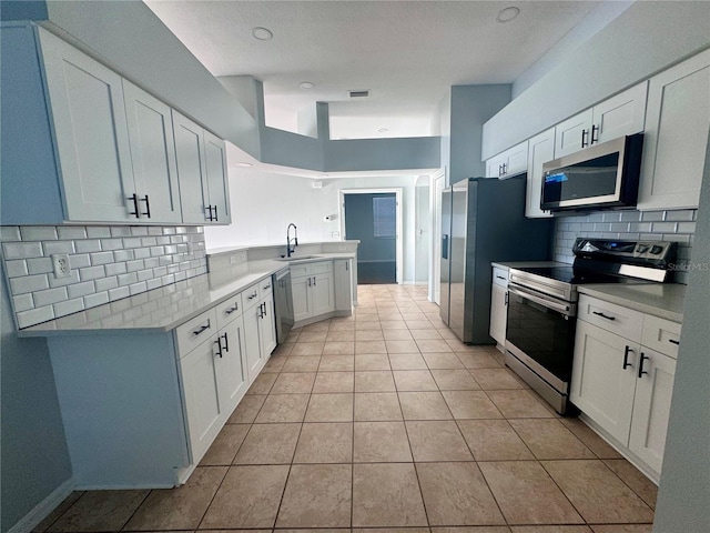 kitchen featuring stainless steel appliances, light countertops, a sink, and backsplash