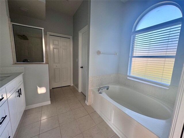 bathroom featuring vanity, baseboards, a shower stall, a bath, and tile patterned floors