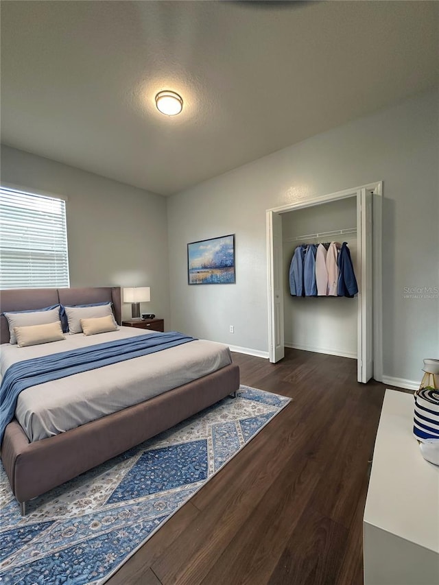 bedroom with dark wood-style floors, a closet, and baseboards