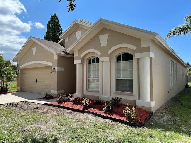 view of front of property with concrete driveway, an attached garage, and stucco siding