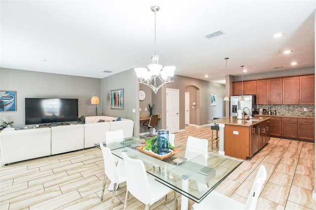 dining area with light wood-type flooring, an inviting chandelier, and sink