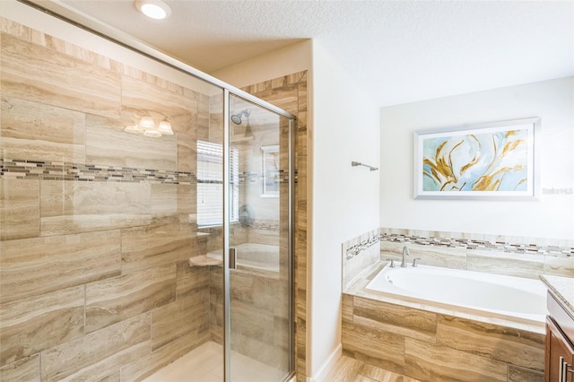 bathroom featuring a textured ceiling, independent shower and bath, and vanity