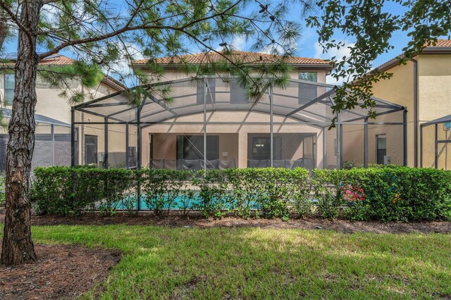 rear view of property with a yard and a lanai