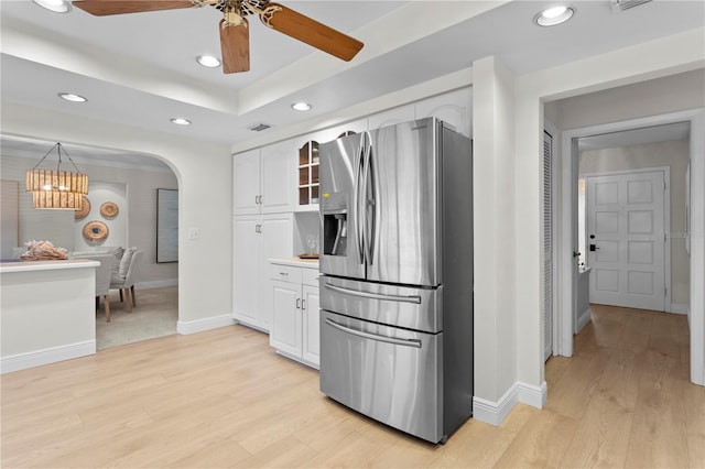 kitchen featuring light hardwood / wood-style floors, stainless steel fridge, white cabinetry, and ceiling fan with notable chandelier