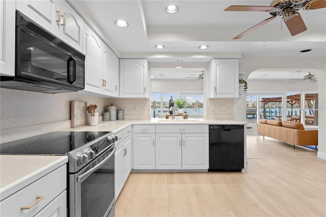 kitchen with black appliances, decorative backsplash, light hardwood / wood-style floors, and white cabinets