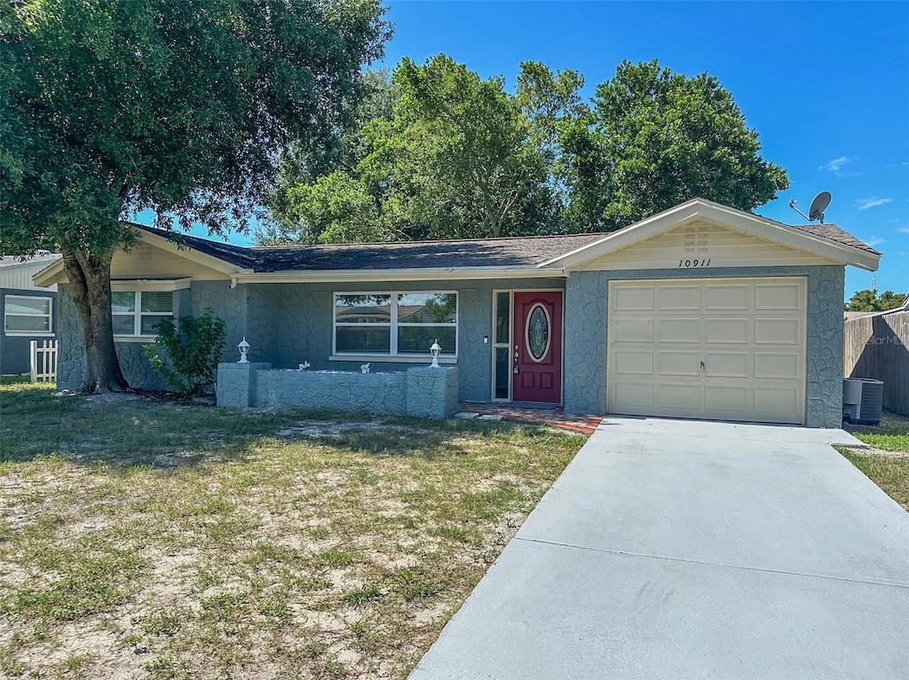 single story home with central AC unit, a garage, and a front yard