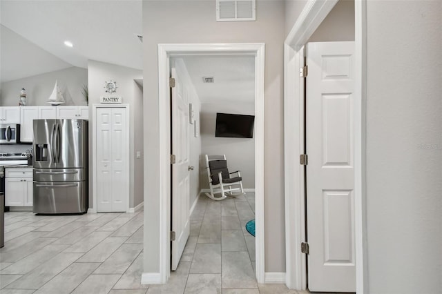 hall with light tile patterned flooring and lofted ceiling