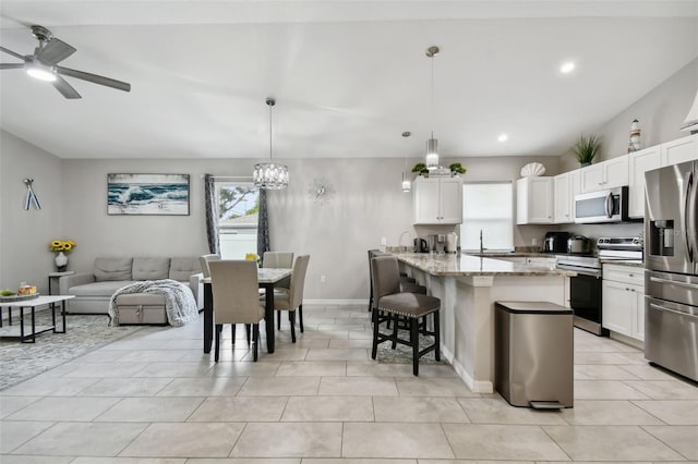 kitchen featuring light stone counters, decorative light fixtures, stainless steel appliances, and white cabinets