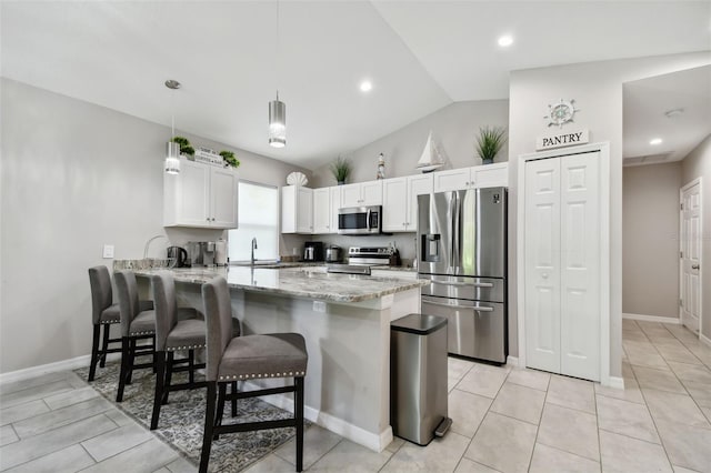 kitchen featuring kitchen peninsula, decorative light fixtures, white cabinetry, stainless steel appliances, and vaulted ceiling