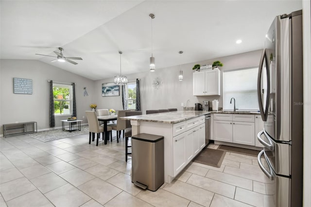 kitchen with light stone counters, white cabinets, lofted ceiling, decorative light fixtures, and appliances with stainless steel finishes