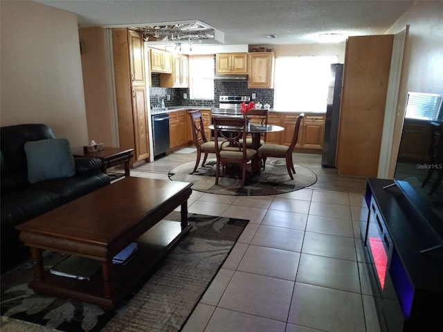 kitchen with appliances with stainless steel finishes, backsplash, a textured ceiling, and light tile patterned flooring