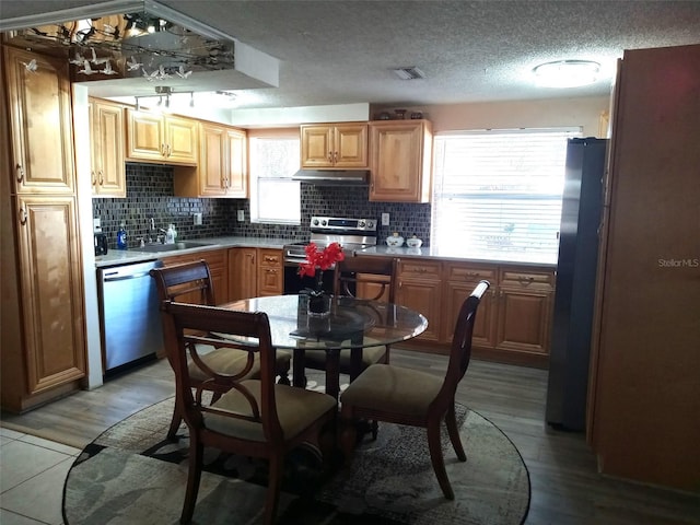 kitchen with backsplash, sink, light hardwood / wood-style flooring, a textured ceiling, and stainless steel appliances