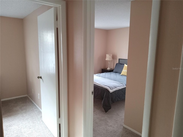 hall with light colored carpet and a textured ceiling