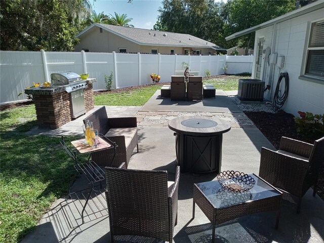 view of patio with central AC unit, exterior kitchen, and an outdoor fire pit