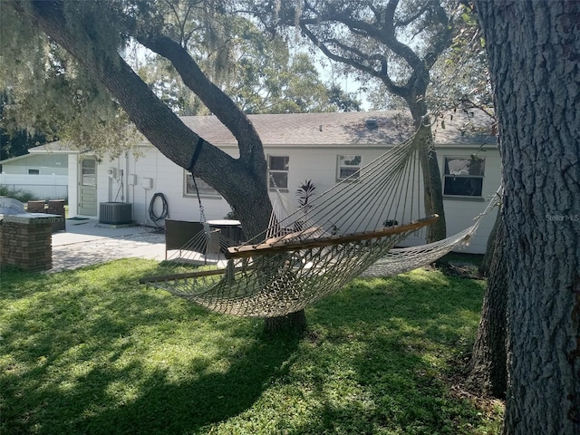 rear view of house featuring cooling unit, a patio area, and a lawn