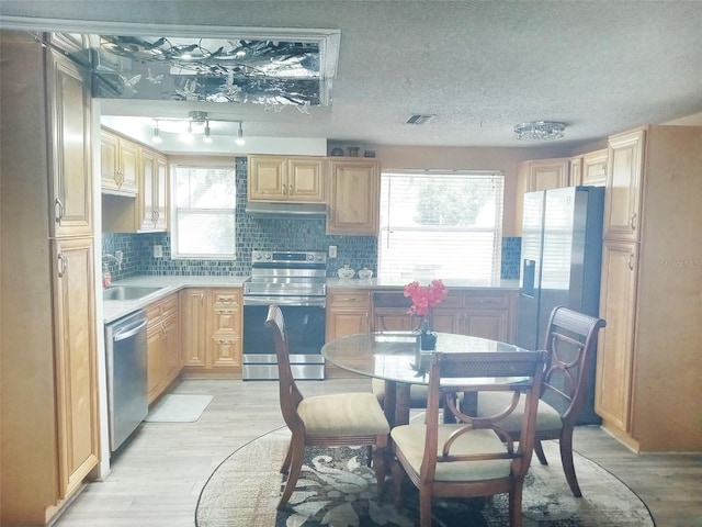 kitchen featuring tasteful backsplash, light brown cabinetry, light hardwood / wood-style flooring, and appliances with stainless steel finishes