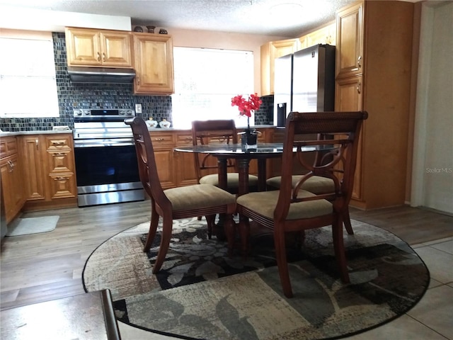 kitchen with light wood-type flooring, decorative backsplash, and electric range