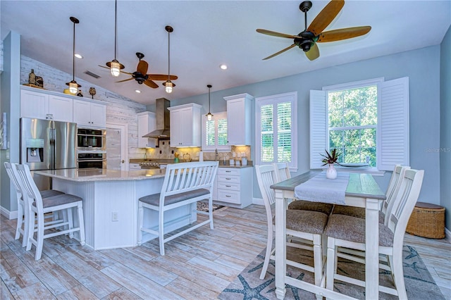 kitchen with a center island, white cabinets, hanging light fixtures, and vaulted ceiling