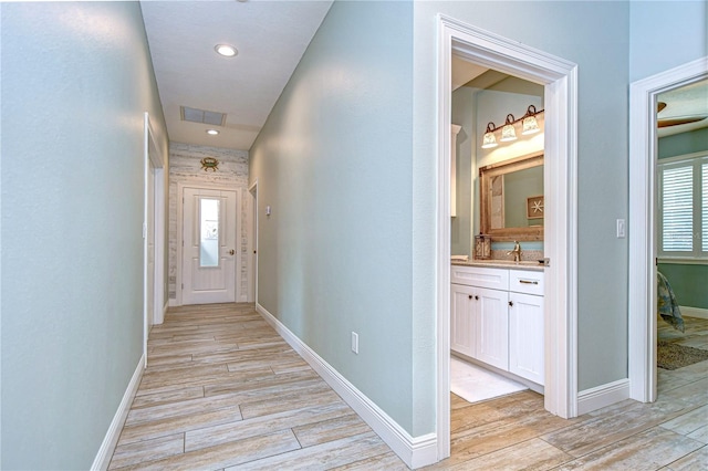 corridor with light hardwood / wood-style floors, a healthy amount of sunlight, and sink